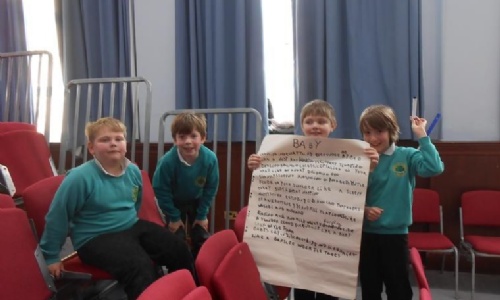Four children with flipchart with handwritten poem on