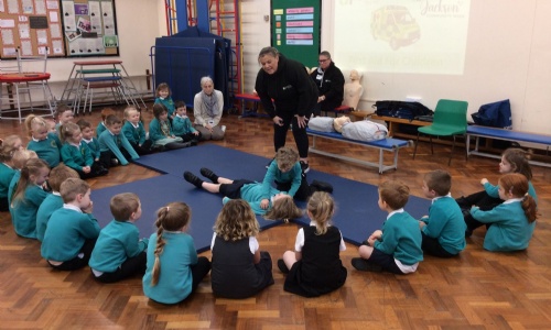 children in a circle watching first aid demonstration
